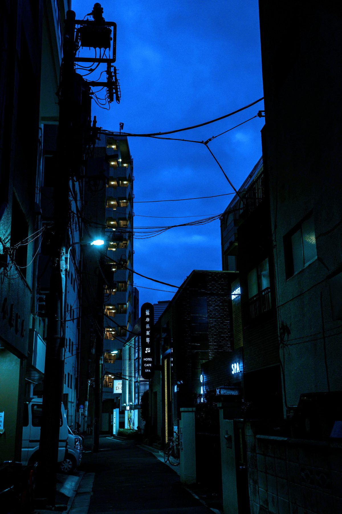夜の鶯谷。路地の上に電線が渡り、集合住宅の灯りが並ぶ